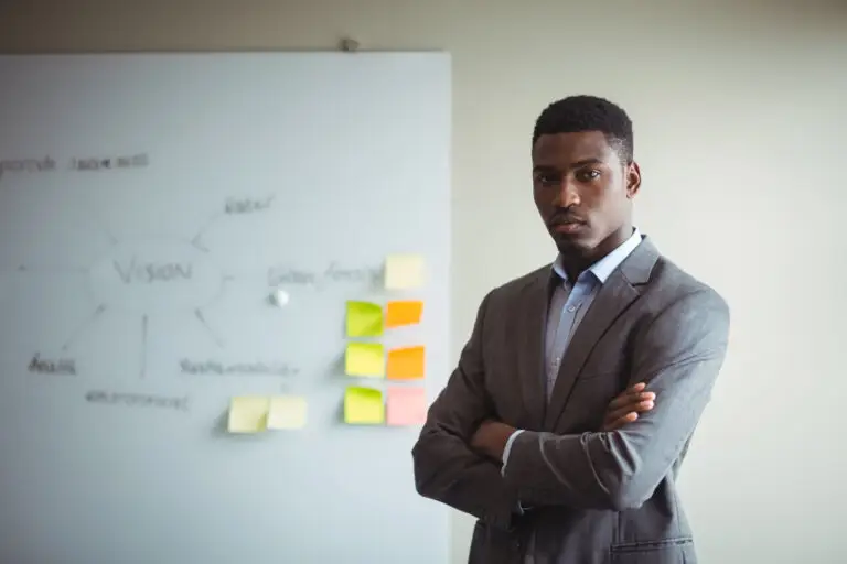 businessman-standing-with-arms-crossed-office-scaled.webp